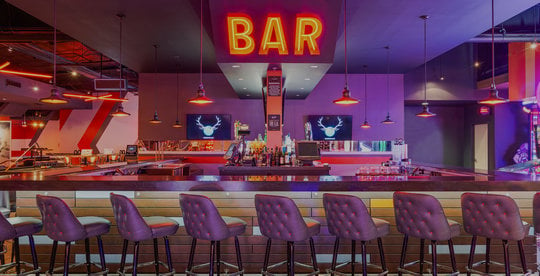 bar stools, a bar, and an orange neon 'bar' sign