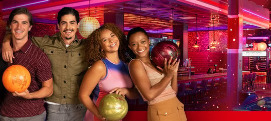 A group of bowlers smiling with bowling balls