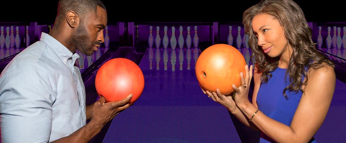man and woman facing each other with bowling balls 