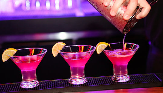 Three pink cocktails on a bar