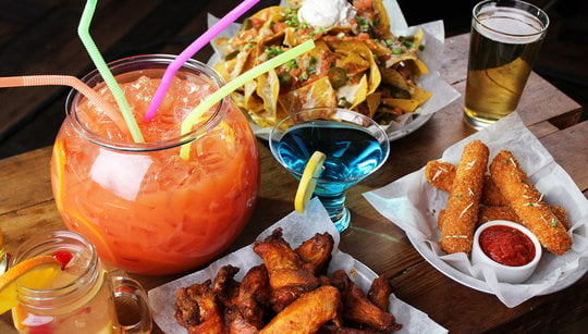 Bar food spread with fishbowl, nachos, mozzarella, buffalo wings