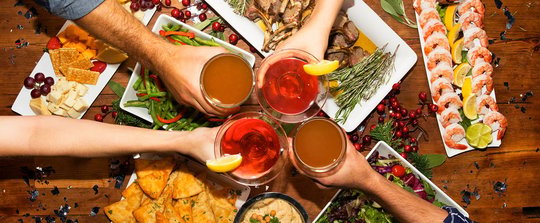group of 4 people cheering drinks over appetizers